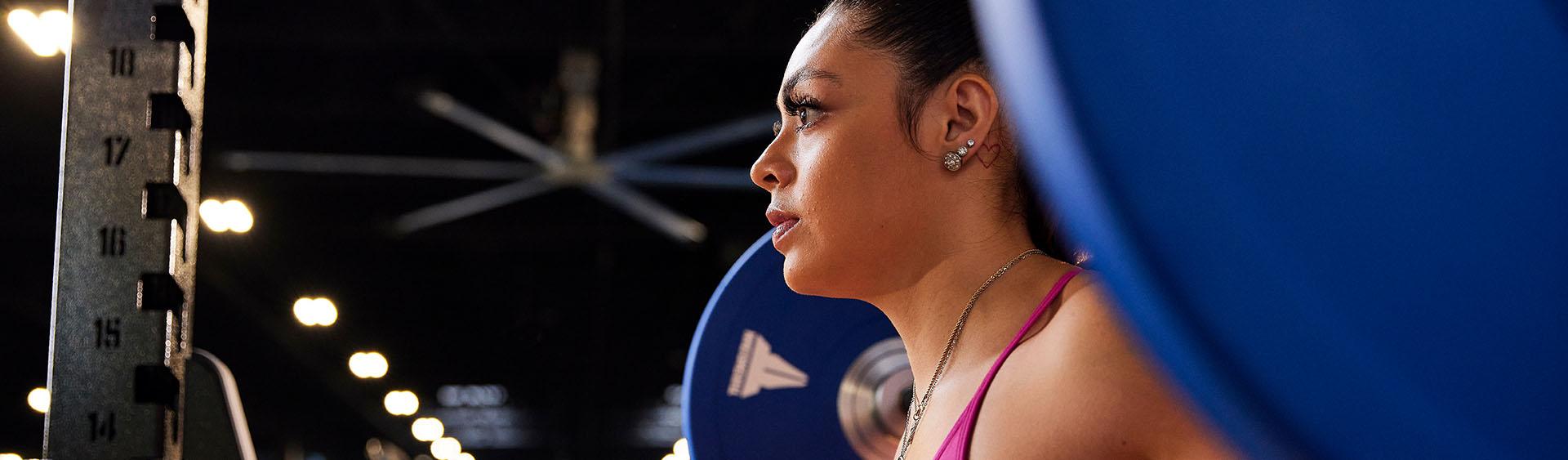 Focused woman lifting a barbell with blue weight plates at the gym