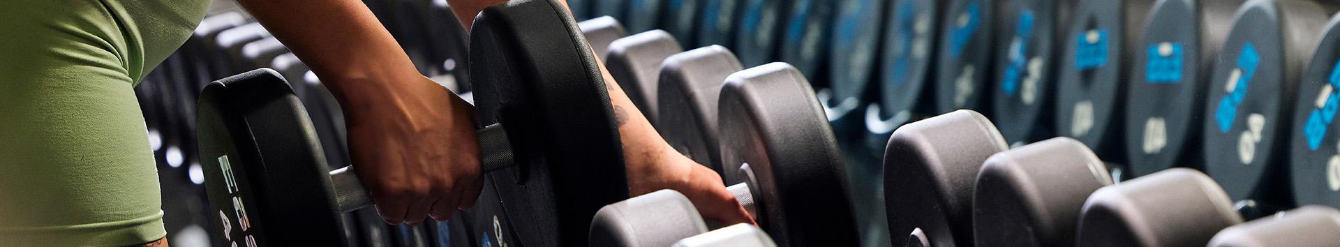 eos member unracking a dumbbell from a long rack of weights