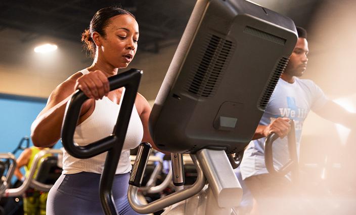 A woman intensely working out on an elliptical machine