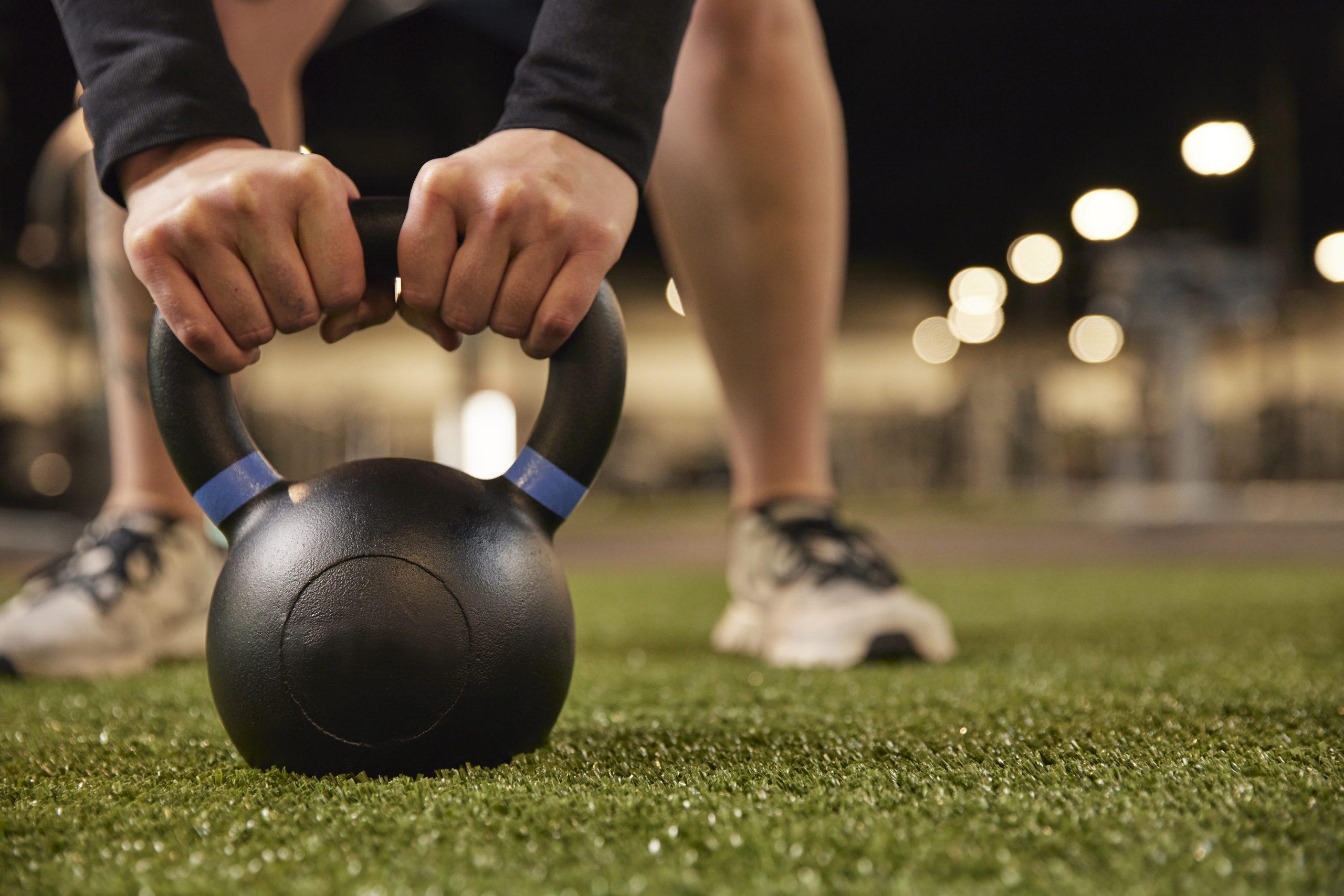 eos gym member lifting a kettle bell on eos branded indoor turf