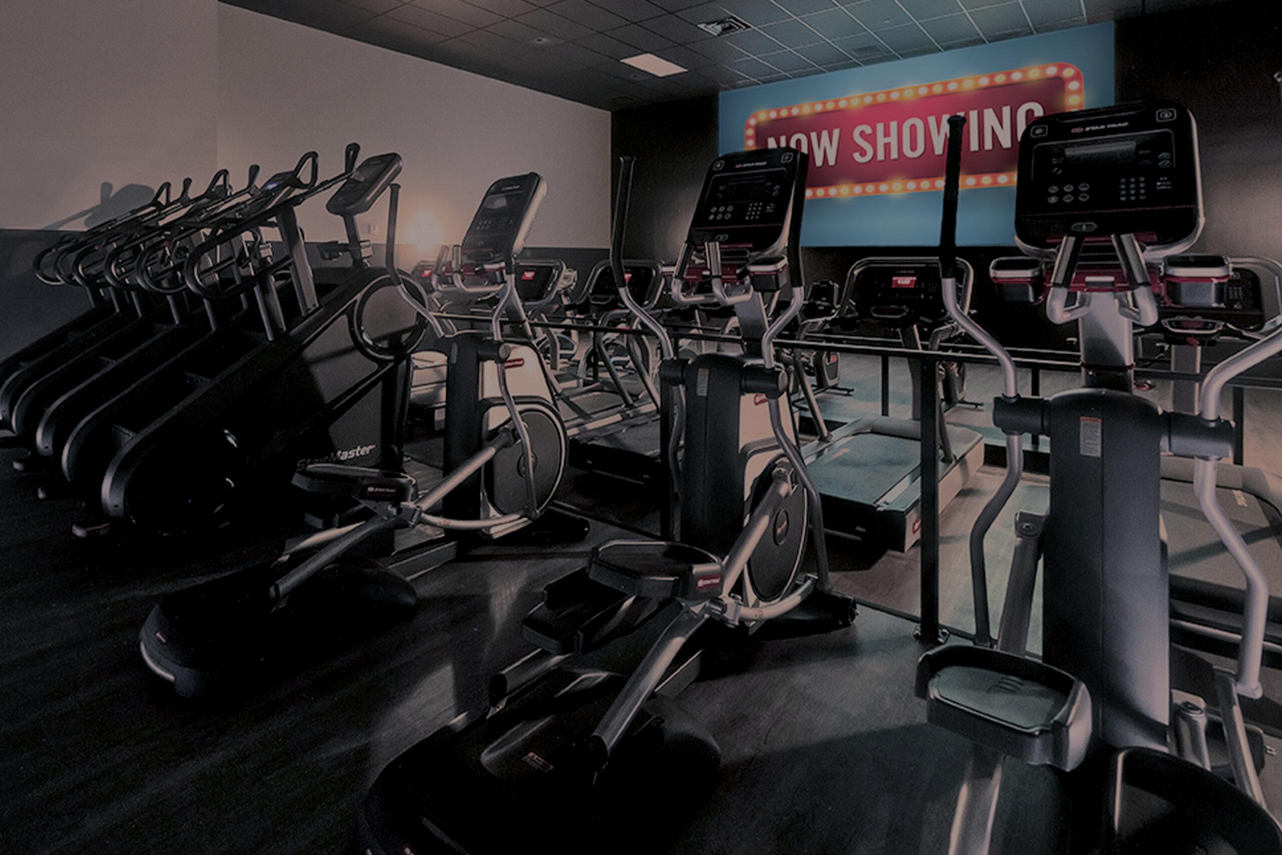 rows of cardio equipment pointed at a large cinematic screen