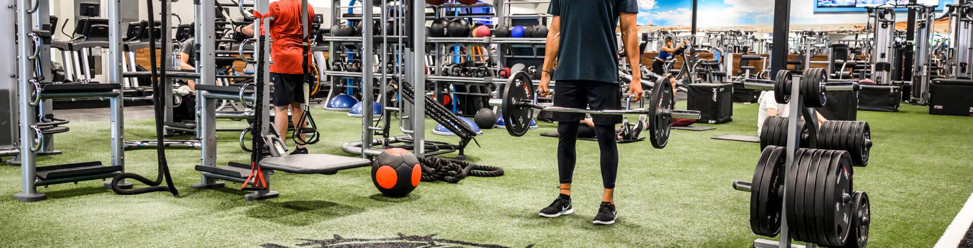 wide shot inside an eos branded gym where multiple members are doing a verity of strength and cardio exercises 