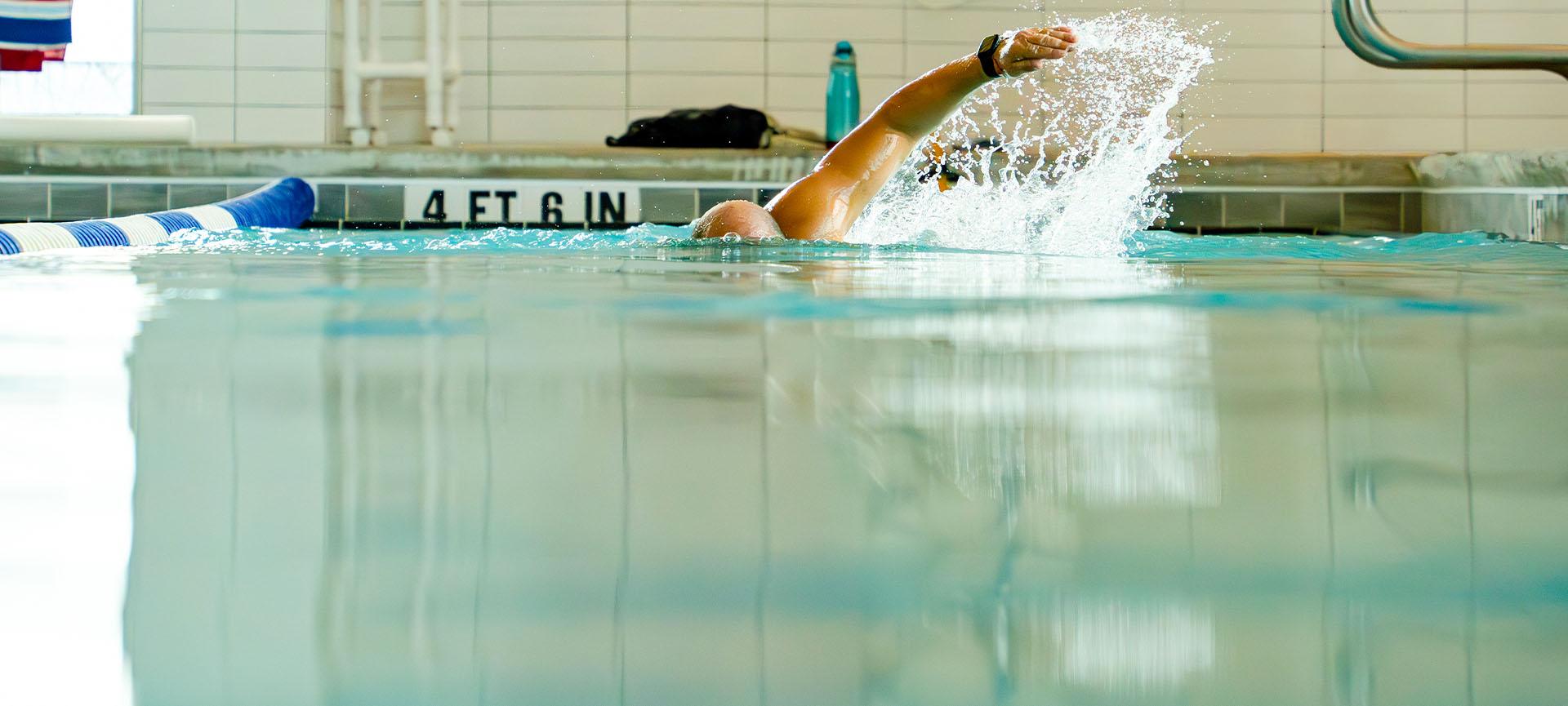 eos gym member freestyle swimming in a clean indoor pool