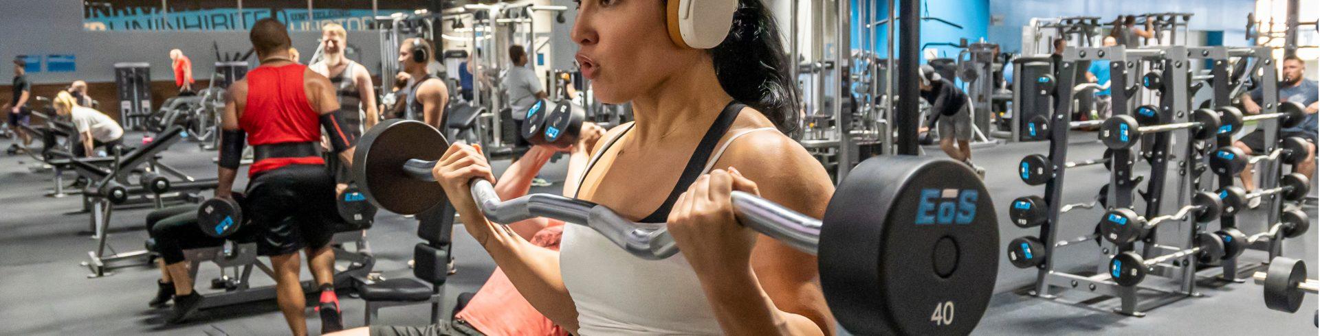 a gym full of eos gym members doing different barbell exercises 