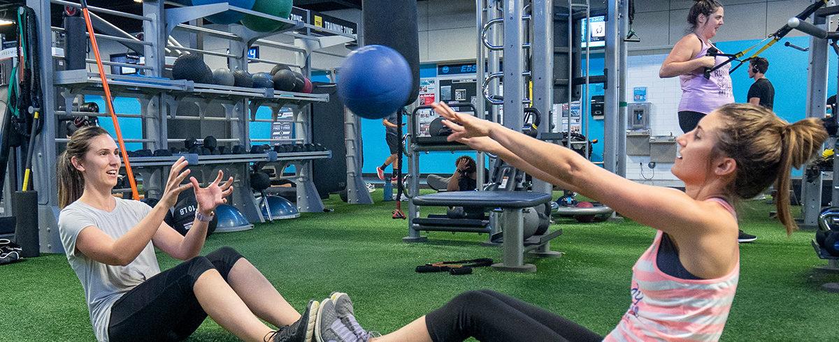 two eos gym members performing a collaborative exercise with a medicine ball