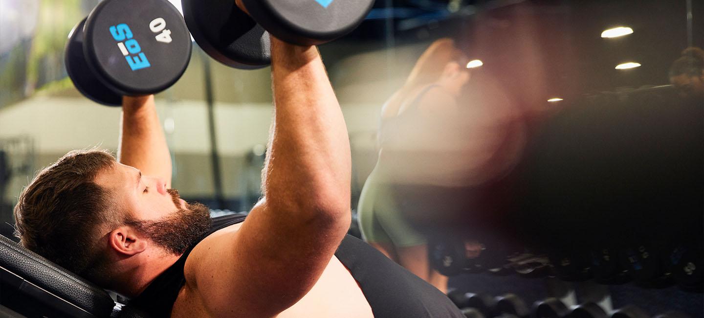 eos member lifting two dumbbells on an incline bench