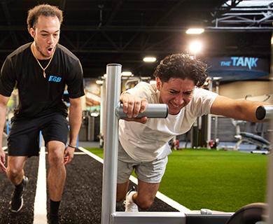 personal trainer motivating eos gym member on sled