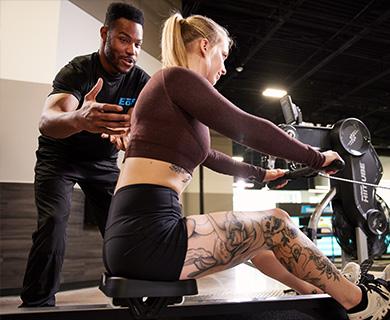 personal trainer spotting eos gym member on cable row machine