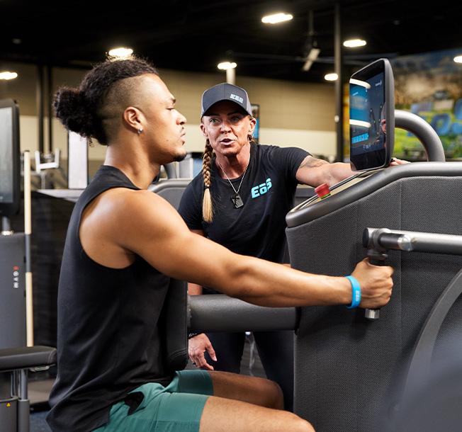 personal trainer hyping an eos gym member doing a pulling exercise on a piece of smart equipment