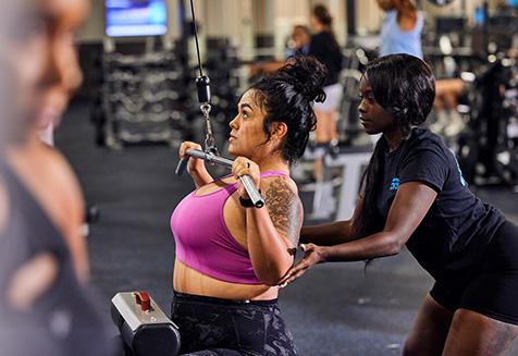 personal trainer showing eos gym member how to use the lat pulldown machine