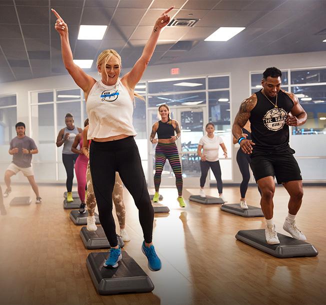 a group shot of many eos gym goes participating in a high energy step class