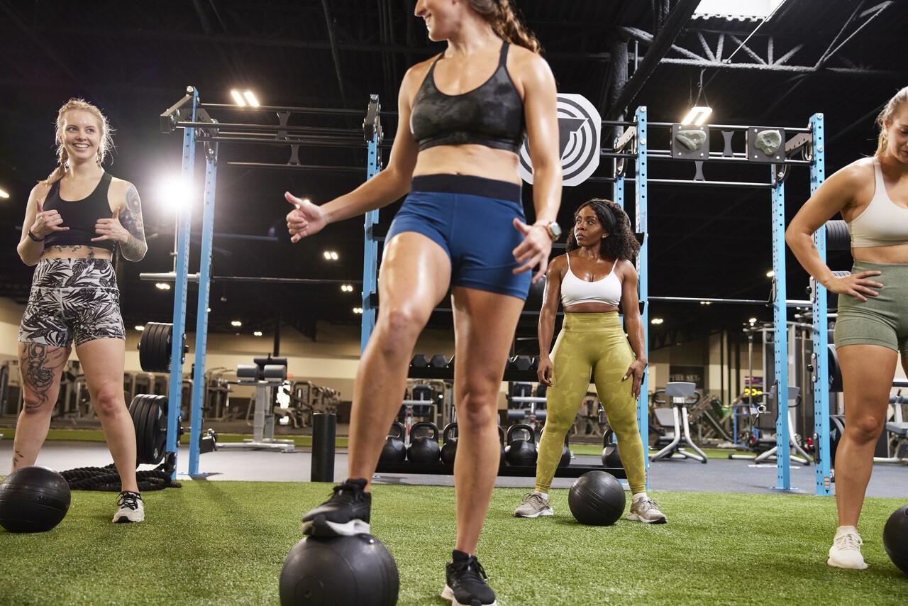 group of smiling athletic eos gym members working out on indoor turf