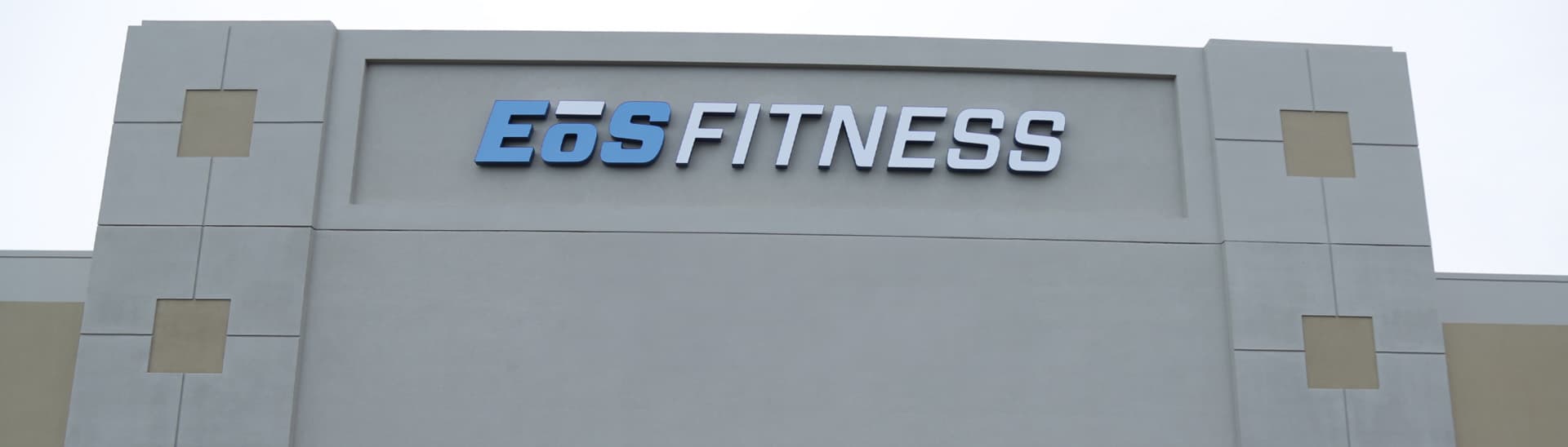 outside shot of a modern eos gym with brick walls and bright blue branding