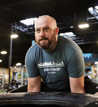 eos gym member flipping a tire in the middle of a well lit eos box gym