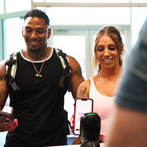 two eos members wearing athletic clothes and smiling while checking in