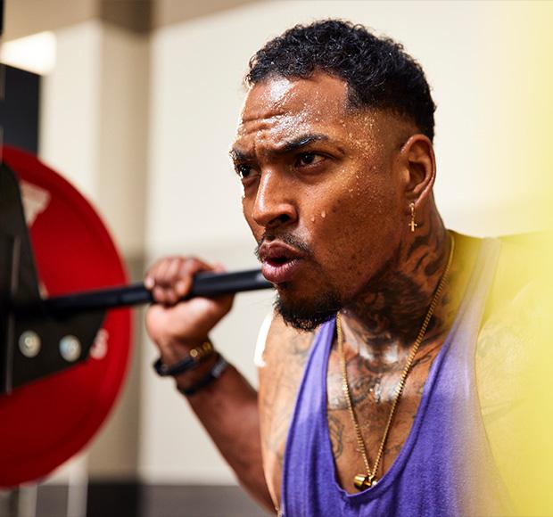 a focused eos gym member at the top of a barbell squat