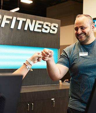 two eos staff at the front desk smiling at each other and fist bumping