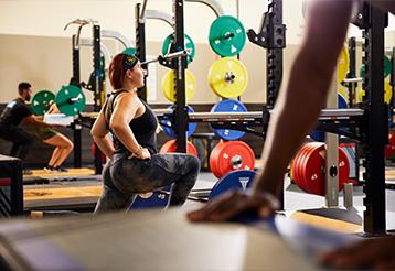 Woman stretching her leg in a lunge position in a gym.