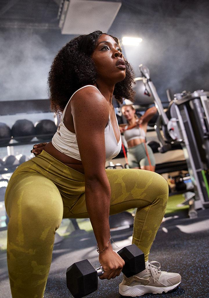 eos gym member performing a single armed dumbbell squat in a well lit eos branded box gym