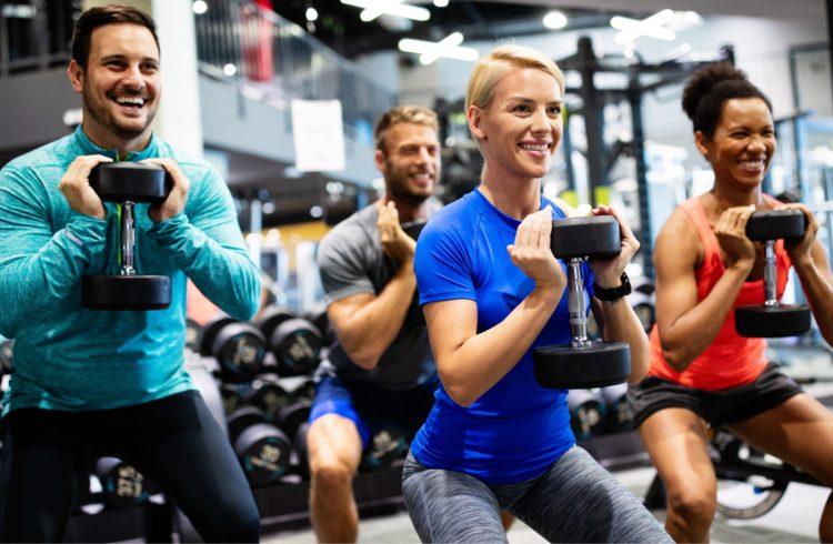 group of athletic eos gym members doing dumbbell squats