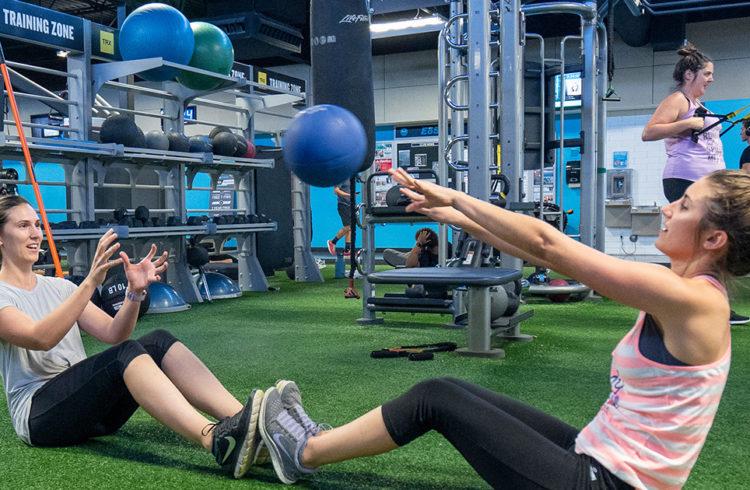 two eos gym members performing a collaborative exercise with a medicine ball