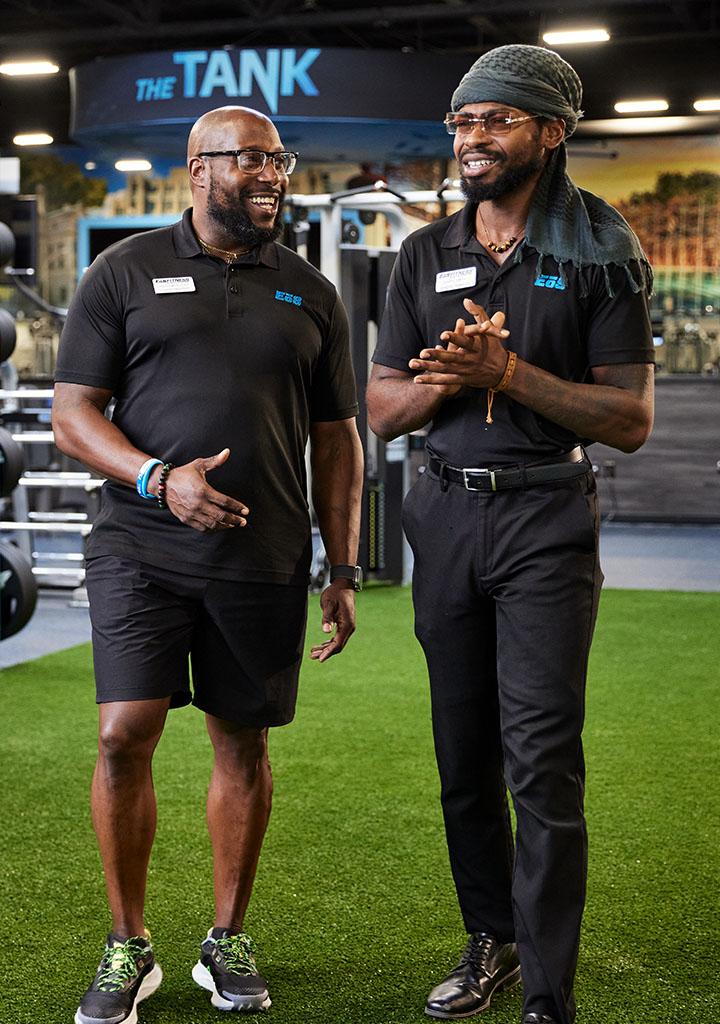 two eos staff standing together and smiling in the middle of a well lit box gym