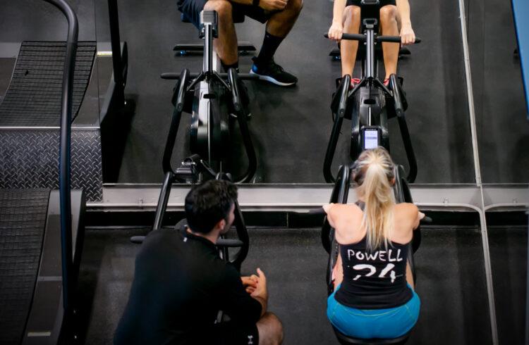 personal trainer showing eos gym member how to properly use rowing machine