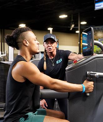 personal trainer hyping an eos gym member doing a pulling exercise on a piece of smart equipment