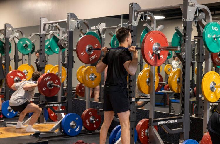 eos gym member barbell squatting in a fully equipped squat rack