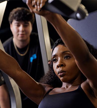 expert coach spotting eos member while they do a chess press on plate loaded machine