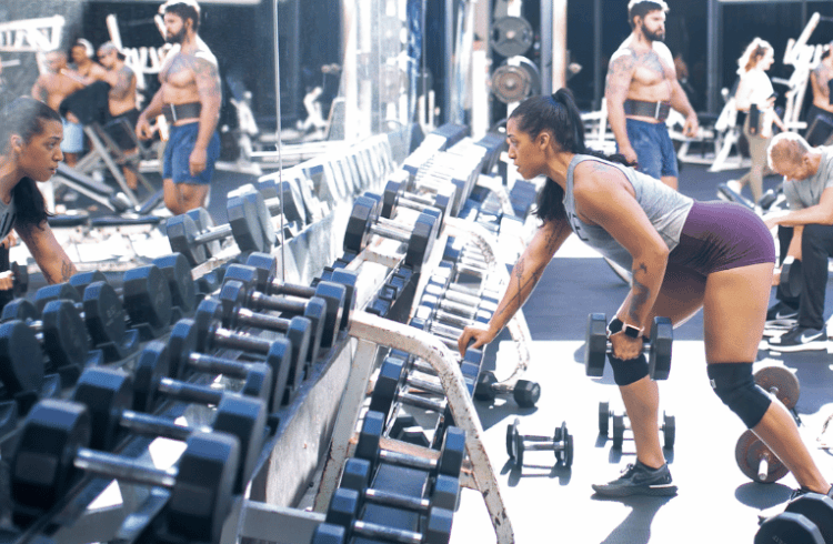a eos gym full of athletic member performing a verity of dumbbell exercises