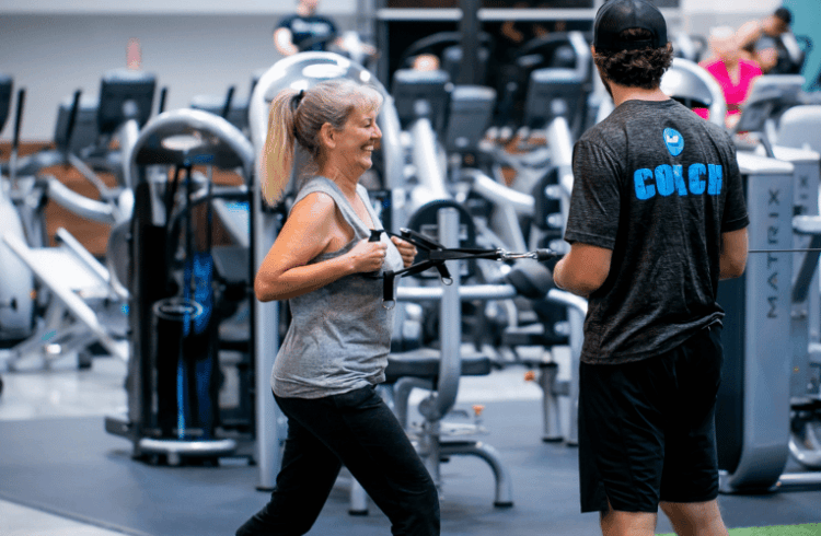 excited eos gym member performing a workout with personal trainer