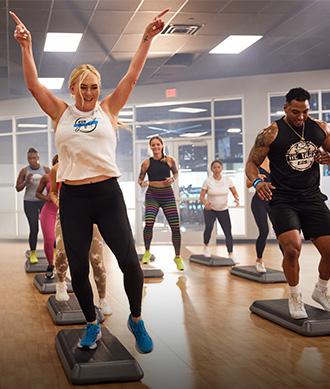 a group shot of many eos gym goes participating in a high energy step class