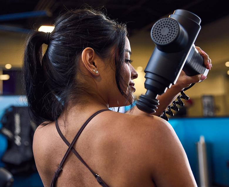 eos gym member using massager on their trap