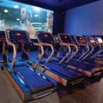 treadmills in front of a movie screen in the MovEoS Cinema at EoS Fitness