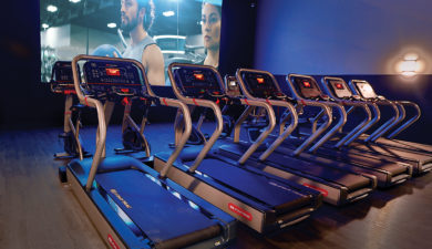 treadmills in front of a movie screen in the MovEoS Cinema at EoS Fitness