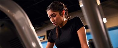A woman focused on her workout, leaning on a gym machine